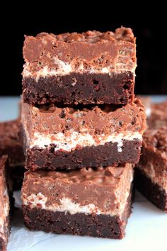 several pieces of brownie with white and chocolate frosting on top, stacked together