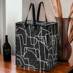 a black and white bag sitting on top of a wooden table next to a vase