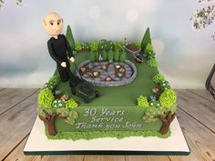 a birthday cake with a man sitting on top of it in the shape of a garden