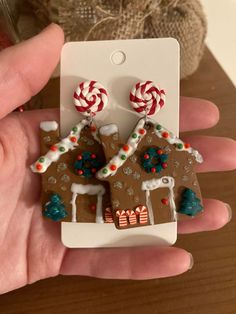 a person holding up a small gingerbread house with candy canes