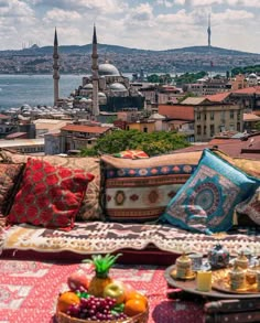 a couch with many pillows on top of it in front of a cityscape