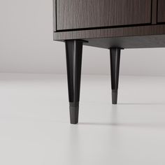 an image of a black and wood dresser on white floor with grey wall in the background