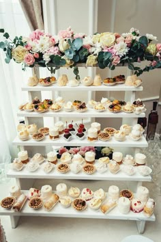 a white shelf filled with lots of different types of cakes and cupcakes on top of it