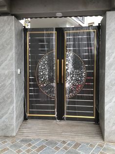 an entrance to a building with two black doors and gold trimmings on the sides