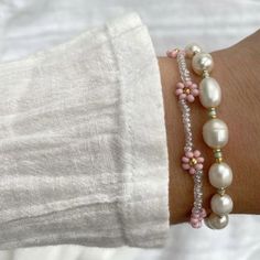 a close up of a person's arm wearing bracelets with pearls and beads