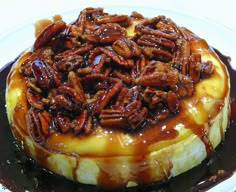 pecans are on top of the cheesecake covered in caramel sauce and drizzled with chocolate