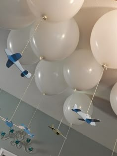 white and blue balloons hanging from the ceiling in a room with an airplane theme on it