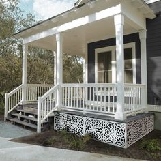 a small house with white porch and black siding