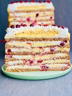 two layers of cake with cranberries and white frosting on a green plate