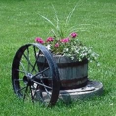 an old wagon with flowers in it is sitting on the grass next to a wheel