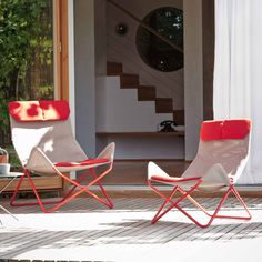 two red and white chairs sitting next to each other on a wooden floor in front of a door