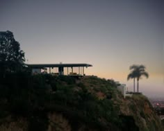 a house on top of a hill with palm trees