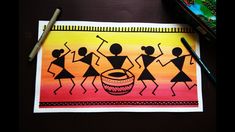 a drawing of people dancing around a drum on top of a table next to paintbrushes