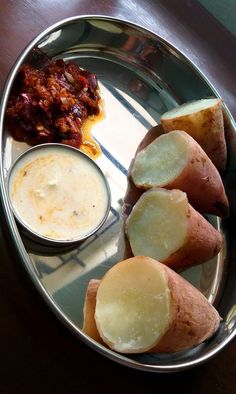 potatoes and dip on a metal plate with some sauce in the bowl next to it