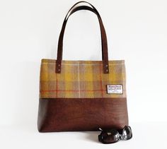 a brown and yellow plaid bag sitting on top of a white table next to a pair of sunglasses