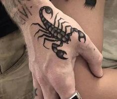 a person with a black scorpion tattoo on their hand