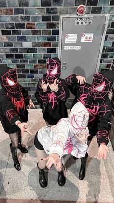 three people in black and pink costumes sitting on the ground