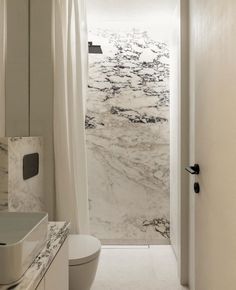 a white bathroom with marble walls and flooring