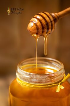 honey dripping from a wooden spoon into a jar