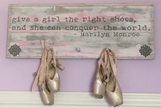 two pairs of shoes are hanging on the wall next to a sign that says give a girl the right shoes and she can conquer the world marilyn monroe