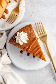 two plates with slices of cheesecake on them next to gold forks and napkins