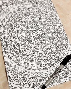 a pen sitting on top of a paper with an intricate design