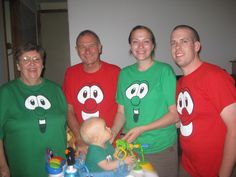 a group of people in matching shirts standing around a table with a baby on it