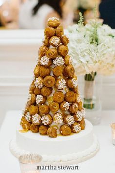 a white table topped with a cake covered in donuts and other desserts on top of it