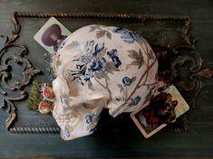 a skull sitting on top of a wooden table next to playing cards and an ornate frame