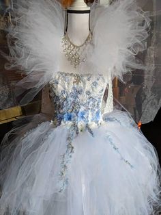 a dress made out of tulle and flowers on display in a store front window