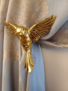 a gold bird curtain tie back on top of a drapes with an intricate design