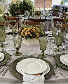 the table is set with plates, silverware and yellow flowers in a white vase