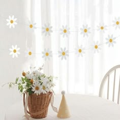 a basket with flowers sitting on top of a table next to a vase filled with daisies