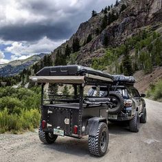 two jeeps parked on the side of a dirt road in front of some mountains