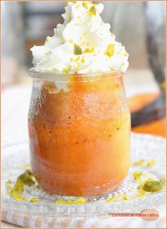 an orange dessert with whipped cream and pistachio topping on a clear glass plate