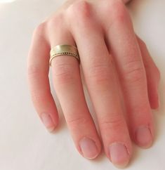 a close up of a person's hand with a gold ring on their finger