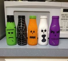 six halloween bottles are lined up in front of a microwave with faces and eyes painted on them