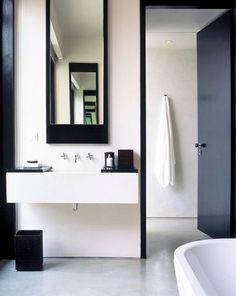 a white bath tub sitting under a bathroom mirror