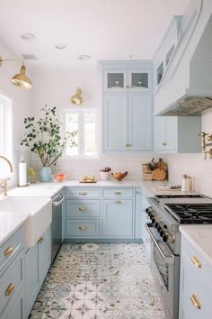 a kitchen with blue cabinets and white counter tops, gold pulls on the hoods