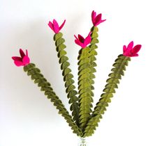 pink flowers are in a clear vase on a white surface with green leaves and stems