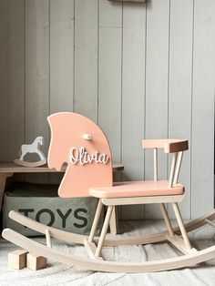 a wooden rocking horse with the name aurora on it's back in front of a gray painted wall