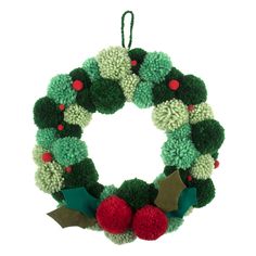 a green and red wreath with pom - poms hanging from it's side