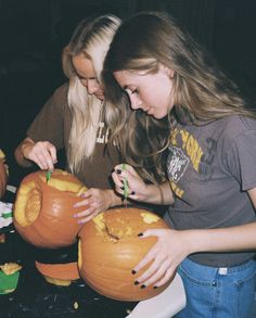 two girls carving pumpkins for halloween