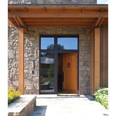 the front entrance to a home with stone walls and wood trimmings on both sides