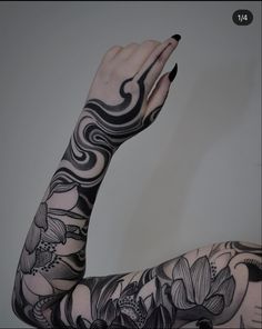 a woman's arm with black and white tattoos on it, holding her hand up to the side