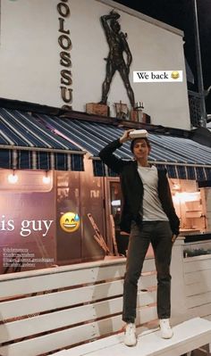 a man standing on top of a bench in front of a building