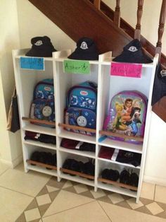 several children's backpacks are lined up on shelves in front of the stairs