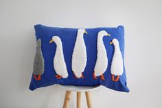 three birds on a blue pillow sitting on a stool