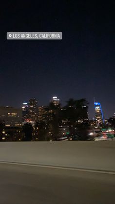 the city skyline is lit up at night as seen from across the freeway in los angeles, california