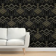 a white couch in front of a black wallpaper with gold art deco design on it